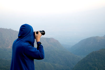 Rear view of person photographing mountains from camera