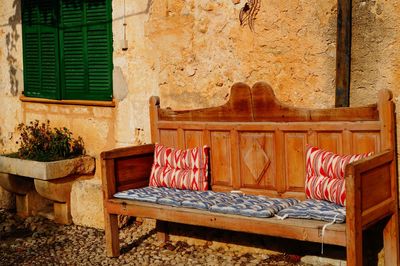Empty bench against wall of house