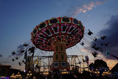 Low angle view of illuminated ferris wheel against sky at dusk