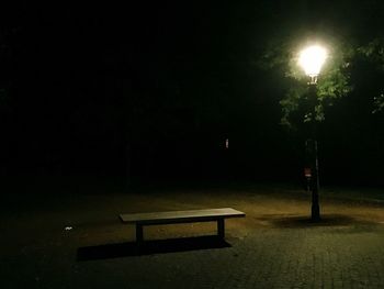 Empty illuminated lights against trees at night