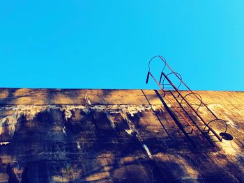 Low angle view of weathered wall against clear blue sky