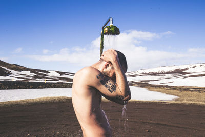 Full length of shirtless man in water against sky