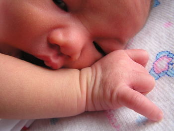 Close-up of newborn baby relaxing on bed