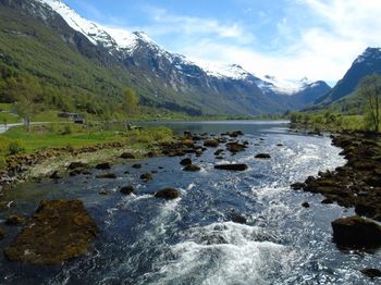 Scenic view of river by mountains against sky