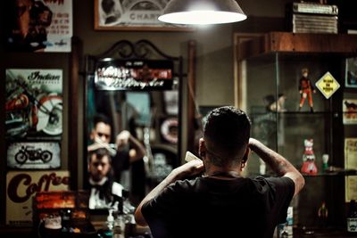 Rear view of man standing at illuminated shop