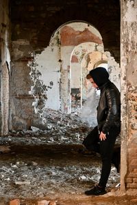 Side view of man standing against old building