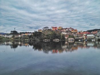 Scenic view of river by buildings in town against sky