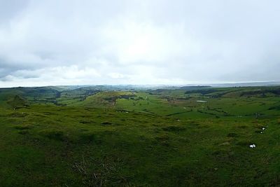 Scenic view of grassy field against cloudy sky