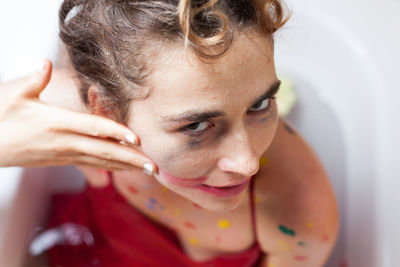 Cropped hand of woman removing lipstick on female friend in bathtub