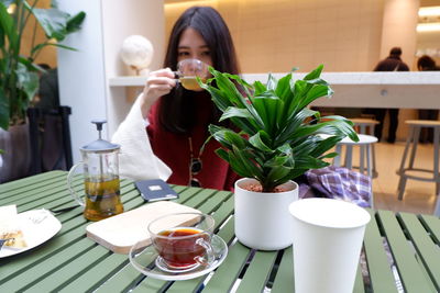 Young woman drinking coffee while sitting at table in cafe