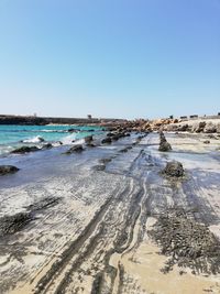 Scenic view of beach against clear blue sky