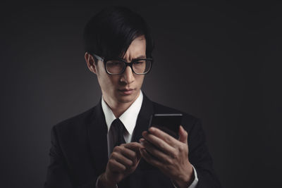 Mid adult man using smart phone against black background