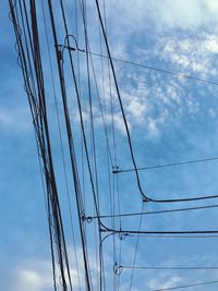 Low angle view of electricity pylon against cloudy sky