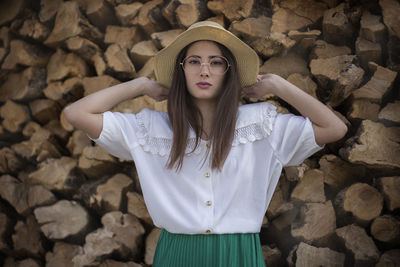 Portrait of young woman standing against rock