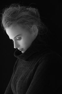 Thoughtful young woman standing against black background