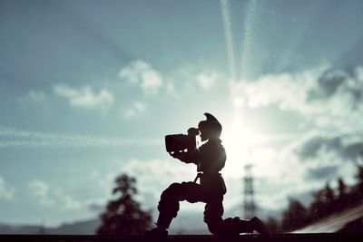 Silhouette man photographing against sky