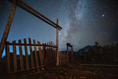 Fence on field against sky at night