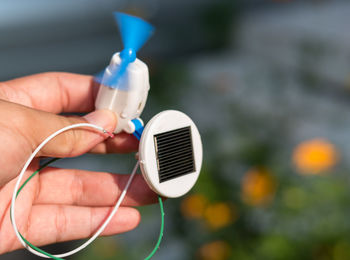 Cropped hand of person holding solar toy fan