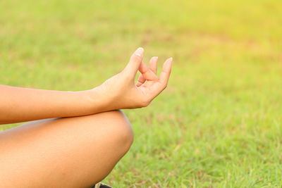 Midsection of woman doing yoga on grass