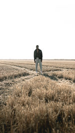 Rear view of man standing on field against clear sky