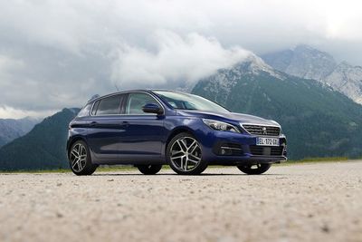 Car on mountain road against cloudy sky