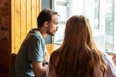 Young couple having dinner in little cafe while sitting at the table near window