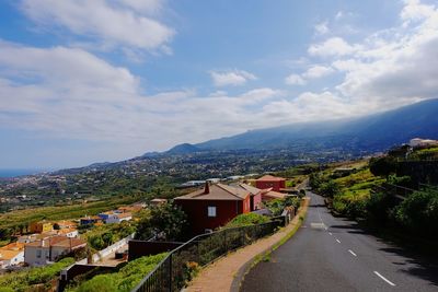 Road by houses against sky