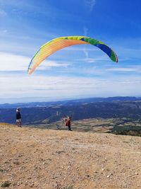 People flying over mountain against sky