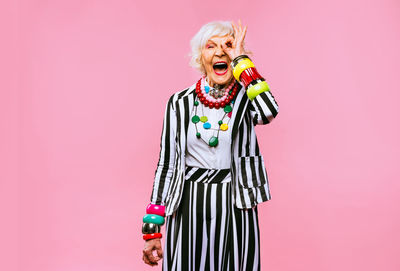 Portrait of senior woman screaming while standing against pink background