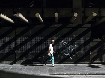 Rear view of man walking on illuminated footpath