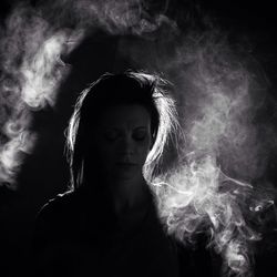 Close-up portrait of woman against black background