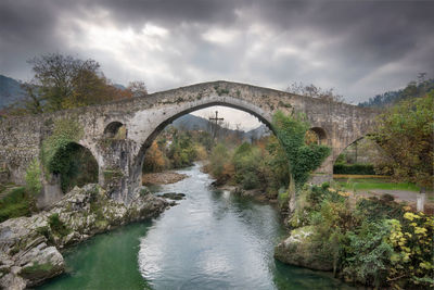 Arch bridge over river against sky