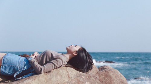 Rear view of woman sitting on beach