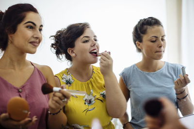 Stylish diverse women doing makeup enjoying time together