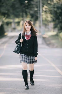 Portrait of young woman standing on road