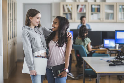 Smiling female students standing in computer lab at high school