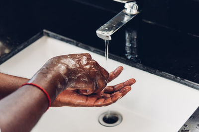 Cropped hand of person cleaning hands in sink