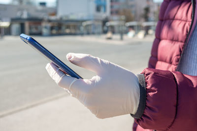 Midsection of man using mobile phone on street