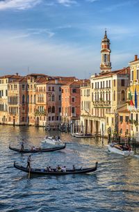 Boats in canal by buildings in city