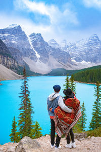 Rear view of men looking at lake against mountain