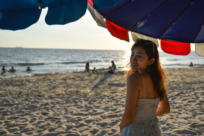 Portrait of smiling young woman standing on beach