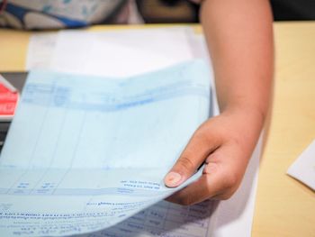 Close-up of hand holding book on table