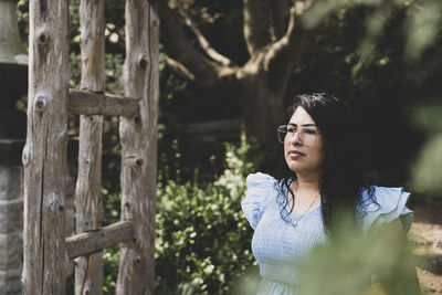 Young woman standing against trees