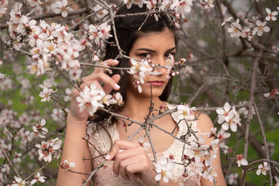 Portrait of young woman holding cherry blossom