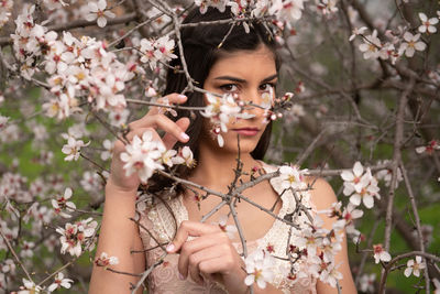 Portrait of young woman with cherry blossoms in spring