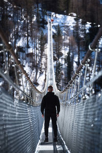 Rear view of man on footbridge in winter