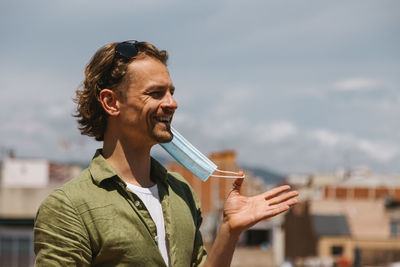 Smiling holding mask standing outdoors