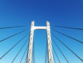 Low angle view of cable bridge against clear blue sky