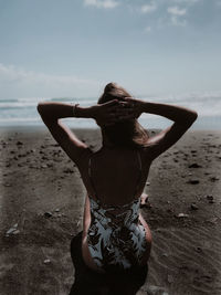 Rear view of woman sitting on beach