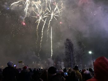 People looking at firework display at night